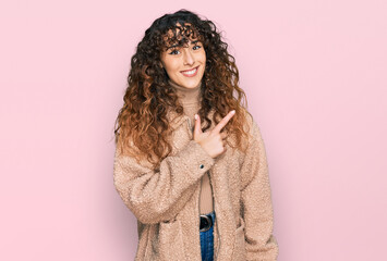 Young hispanic girl wearing winter clothes cheerful with a smile of face pointing with hand and finger up to the side with happy and natural expression on face