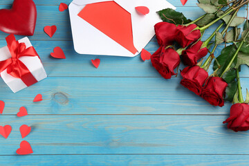Fototapeta na wymiar Flat lay composition with beautiful red roses and gift box on light blue background, space for text. Valentine's Day celebration