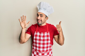 Young hispanic man wearing baker uniform showing and pointing up with fingers number six while smiling confident and happy.