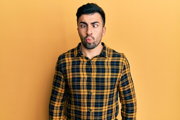 Young hispanic man wearing casual clothes making fish face with lips, crazy and comical gesture. funny expression.