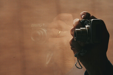 hand holds camera with reflection on the window