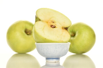 One half green apple of Renet Simirenko in a saucer and two apples in the background, isolated on white.