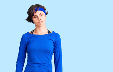 Beautiful young woman with short hair wearing training workout clothes relaxed with serious expression on face. simple and natural looking at the camera.