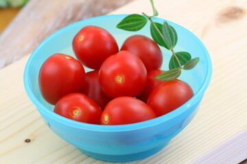 Ripe and sweet cherry tomatoes in blue plastic bowl
