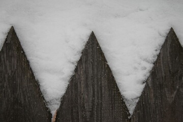 abstraction of gray and white old wooden fence covered with snow