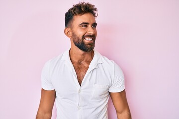 Obraz premium Young hispanic man wearing casual clothes looking away to side with smile on face, natural expression. laughing confident.