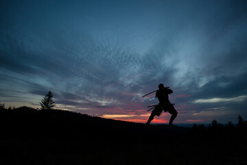 Silhouette of a Japanesesamurai with sword training during sunset © semisatch