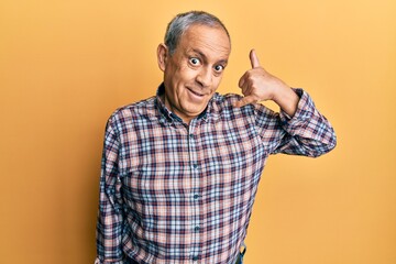Naklejka premium Handsome senior man with grey hair wearing casual shirt smiling doing phone gesture with hand and fingers like talking on the telephone. communicating concepts.