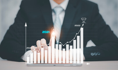 Businessman touch line arrow with number 2021 on the graph chart of stock market ,Technology Process System Business with Investment and stock market concept gain and profits with faded number charts.