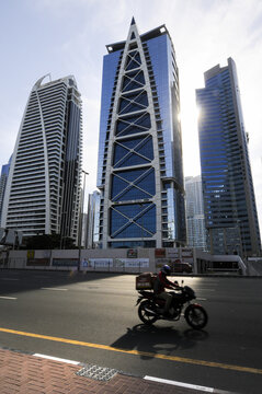 Vue sur une route et des buildings &agrave; Duba&iuml;. Une motocyclette au premier plan, les gratte-ciel au second, et le soleil descendant formant un joli contre-jour en clair-obscur.