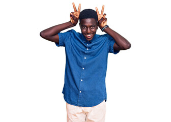 Young african american man wearing casual clothes posing funny and crazy with fingers on head as bunny ears, smiling cheerful