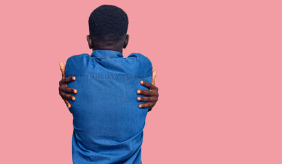 Young african american man wearing casual clothes hugging oneself happy and positive from...