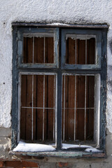 Wooden window with bars on it, blue frame, white wall, snow on sill