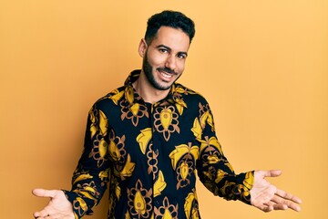 Young hispanic man wearing casual shirt clueless and confused expression with arms and hands...