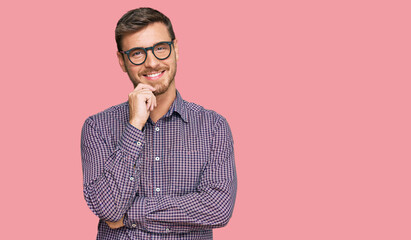 Obraz premium Handsome caucasian man wearing casual clothes and glasses looking confident at the camera with smile with crossed arms and hand raised on chin. thinking positive.