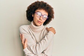 Young hispanic girl wearing casual clothes and glasses hugging oneself happy and positive, smiling...