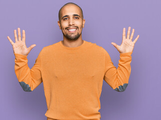 Hispanic adult man wearing casual winter sweater showing and pointing up with fingers number ten while smiling confident and happy.