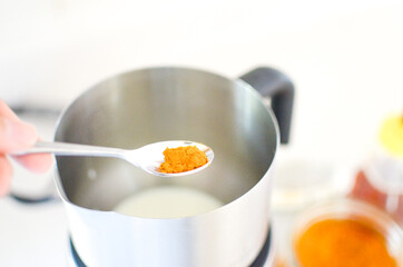 Adding turmeric in a metal cup making turmeric Cappucino