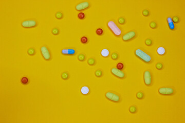 Fototapeta na wymiar Pharmaceutical colorful pills and capsules on yellow background. A large number of tablets on the surface. The concept of modern treatment, pharmacy, healthcare. 