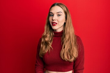 Young blonde woman wearing turtleneck sweater relaxed with serious expression on face. simple and natural looking at the camera.
