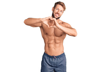 Fototapeta premium Young caucasian man standing shirtless smiling in love doing heart symbol shape with hands. romantic concept.