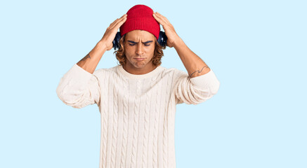 Fototapeta premium Young hispanic man listening to music using headphones suffering from headache desperate and stressed because pain and migraine. hands on head.