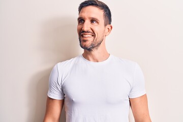 Obraz premium Young handsome man wearing casual t-shirt standing over isolated white background looking to side, relax profile pose with natural face and confident smile.