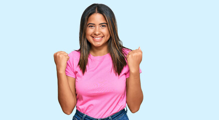 Fototapeta na wymiar Young latin girl wearing casual clothes celebrating surprised and amazed for success with arms raised and open eyes. winner concept.