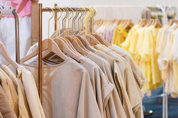 Close up image of female cotton clothes in neutral colors tone hanging on clothing rack for sale in boutique fashion store at shopping mall