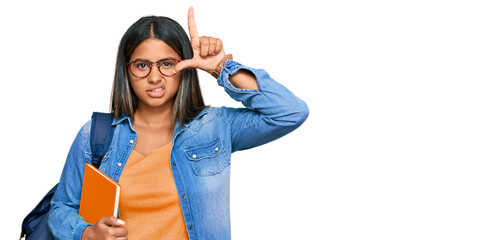 Young latin girl wearing student backpack and holding books making fun of people with fingers on...