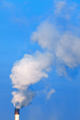 Fototapeta na wymiar Pipe with Industrial Smoke Against Blue Sky 