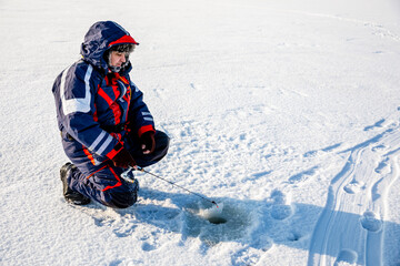 Fototapeta na wymiar A fisherman is fishing with a winter spinning rod on a frozen lake