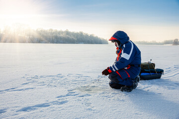A fisherman is fishing with a winter spinning rod on a frozen lake.