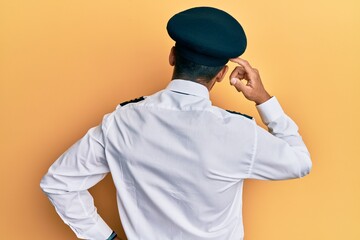 Handsome hispanic man wearing airplane pilot uniform backwards thinking about doubt with hand on...