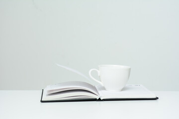 There is a white cup on the open diary. The concept of education, business.