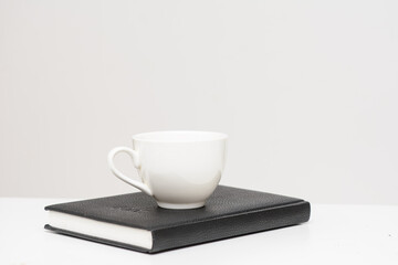 There is a white cup on the diary. The concept of education, business.