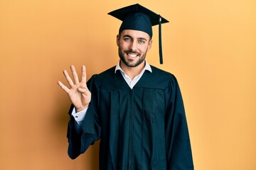 Young hispanic man wearing graduation cap and ceremony robe showing and pointing up with fingers...