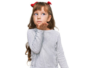 Little caucasian girl kid wearing casual clothes looking at the camera blowing a kiss with hand on air being lovely and sexy. love expression.