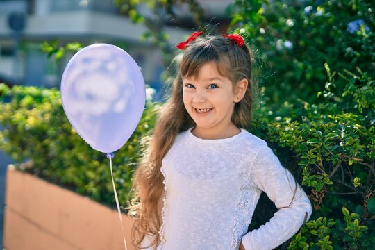 Adorable caucasian child girl  smiling happy playing with ballon at the park.