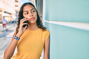 Fototapeta premium Young african american girl with unhappy expression talking on the smartphone at city.
