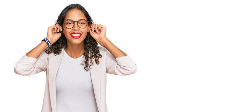 Young african american girl wearing business clothes smiling pulling ears with fingers, funny gesture. audition problem