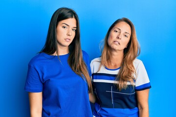 Hispanic family of mother and daughter wearing casual clothes over blue background looking sleepy and tired, exhausted for fatigue and hangover, lazy eyes in the morning.
