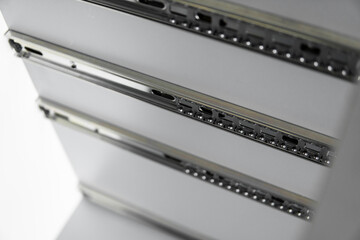Stainless telescopic bayonet drawer slide guides, installed on a kitchen cabinet from gray...