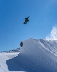Snowboarder performing an inverted trick in a snowpark in Austria on a sunny day