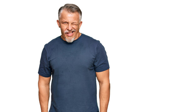 Middle age grey-haired man wearing casual clothes winking looking at the camera with sexy expression, cheerful and happy face.