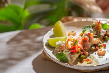 Spring rolls with shrimps and vegetables in a white plate on a monstera background