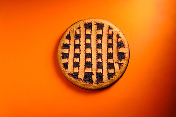 Berry pie in a baking dish on an orange background