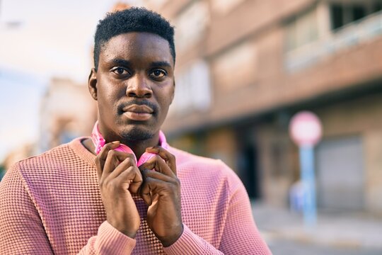 Young african american man with serious expression using headphones at the city.