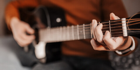 Man learning to play guitar with the help of online learning at home