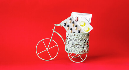 On a red background, a toy vintage bike with pills from the virus